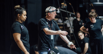 A man in a black t-shirt and head-torch is holding a cable in his hand.