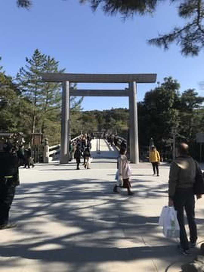 In the mid distance there is a large white wooden Shinto shrine gate.